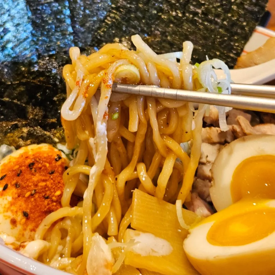 A bite of abura soba noodles, scallion, and meat on seaweed
