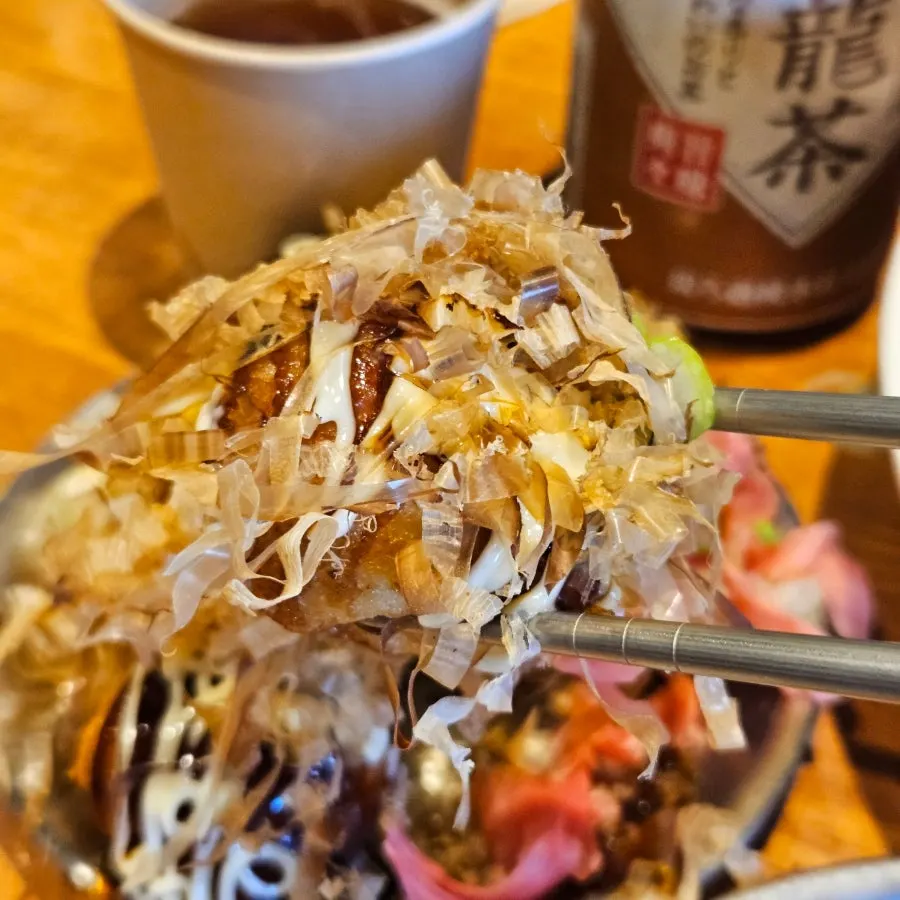 A piece of takoyaki lifted with chopsticks
