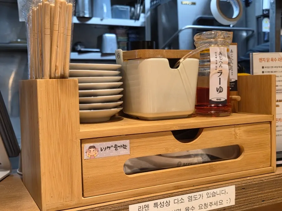 Chopstick and spoon holder with whole peppercorn and house-made la-yu on the table