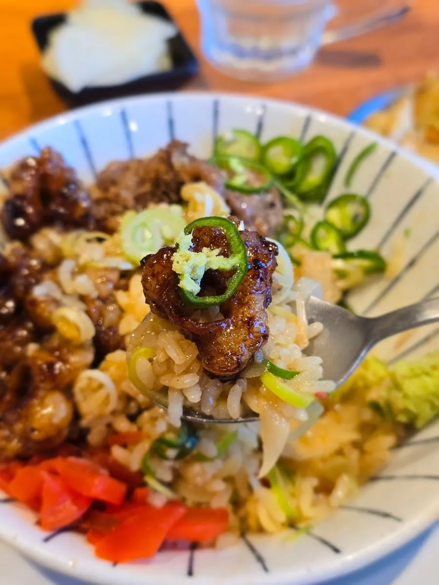 A bite of hormone-don with vegetables scooped together