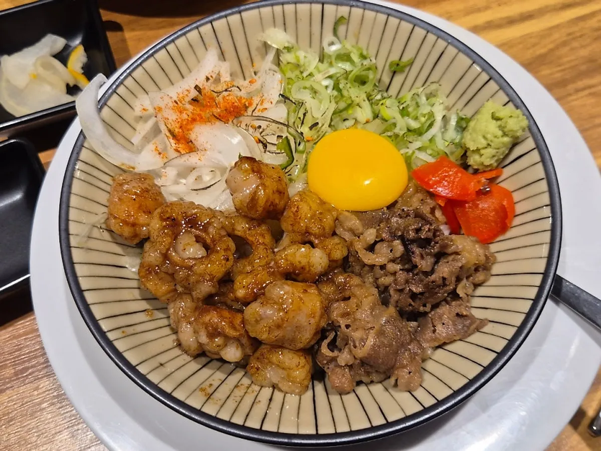 Hormone-don topped with flame-grilled beef intestine and egg yolk