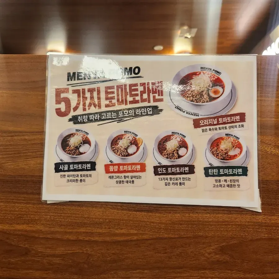 Menu board listing the tomato ramen lineup at Menya Pomo