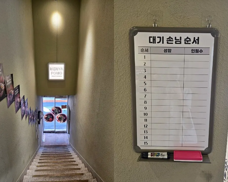 Stairs up to the 2nd floor and the waiting order blackboard at Menya Pomo Seoul Forest Branch