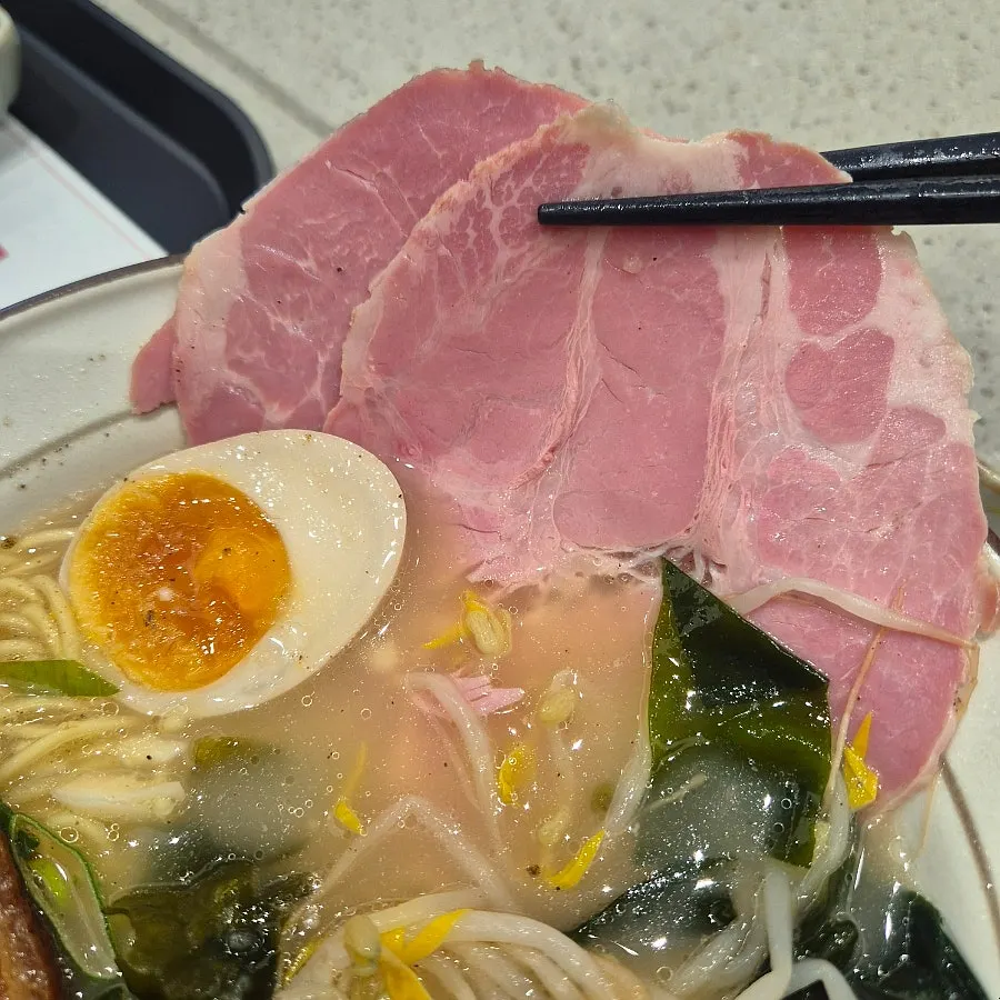 Close-up comparing the size of the dongpo pork topping on the ramen