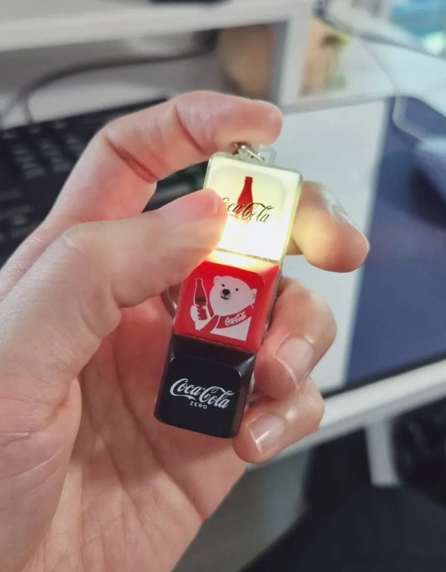 Two Coca-Cola keycaps held in hand