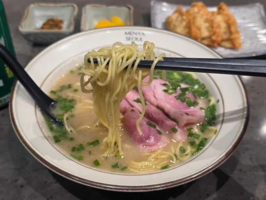 Pale, mild tonkotsu broth scooped up with a spoon