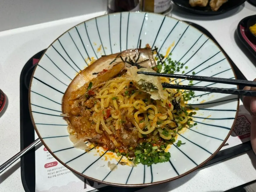 A bite of mazesoba with a large piece of pork belly