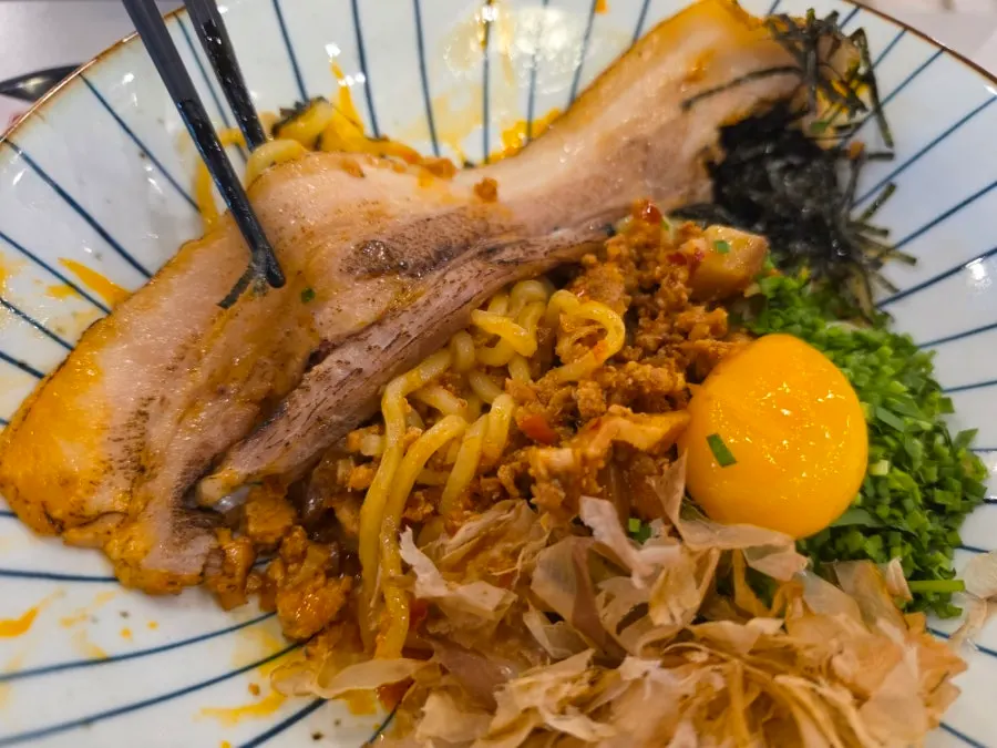 Whole pork belly chashu and egg yolk on top of the noodles