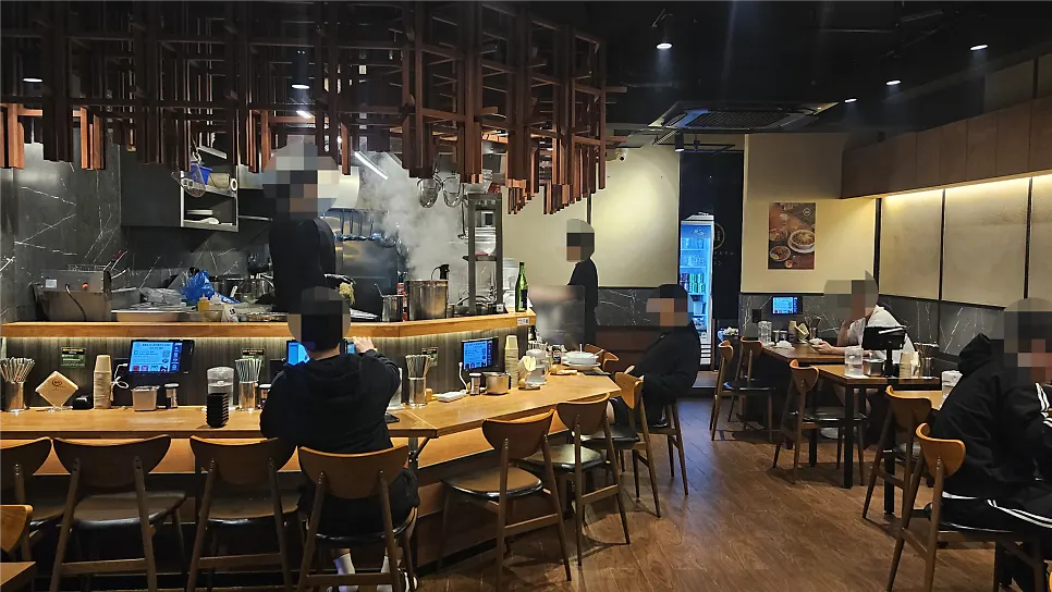 Bar seats facing the kitchen where cooking is visible