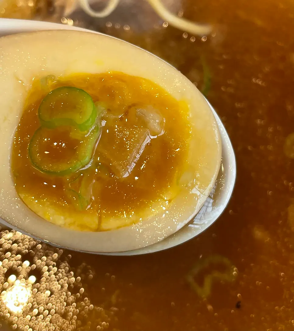 A thick slice of chashu being lifted with chopsticks