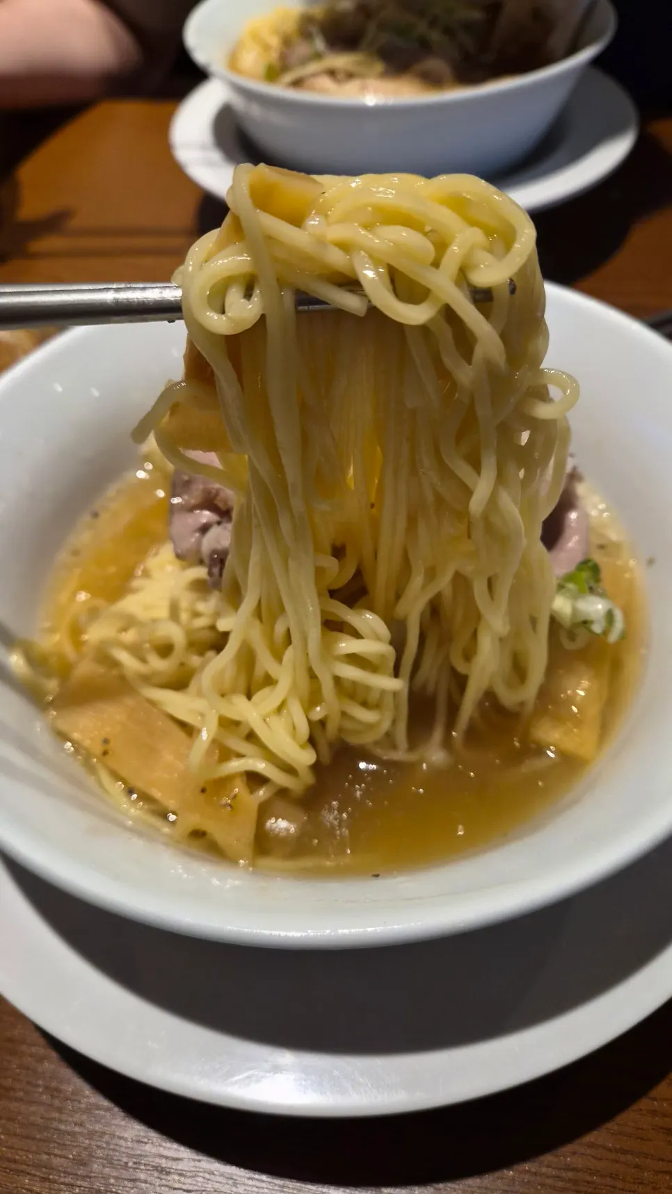 A bite of shio ramen swapped with the shoyu ramen