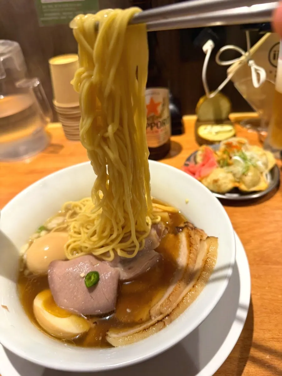 Shoyu ramen noodles lifted with chopsticks