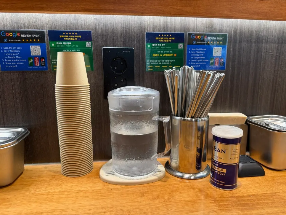 Paper cups, a water pitcher, and chopsticks set on the table
