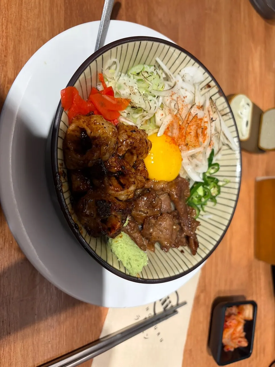 Full shot of horumon-don topped with grilled beef intestine and egg yolk