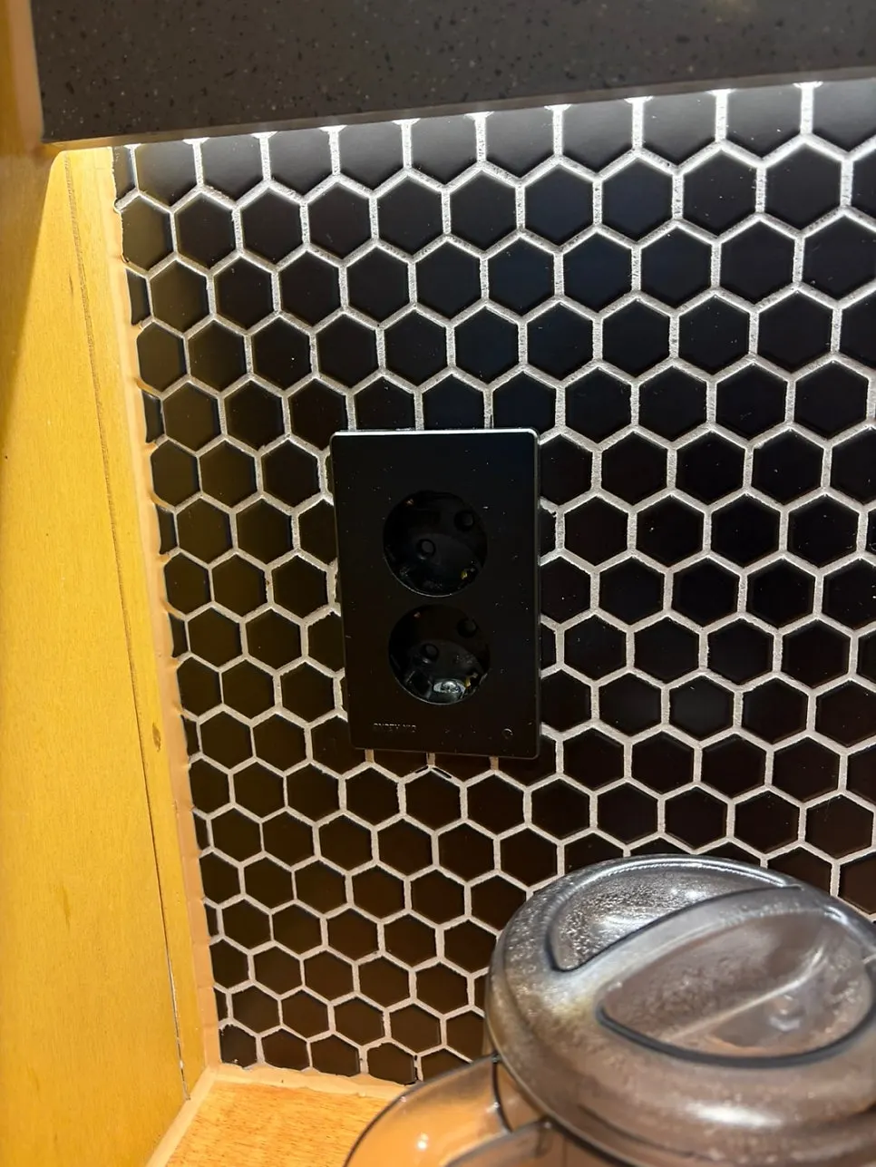 An electrical outlet installed on the wall by the seat