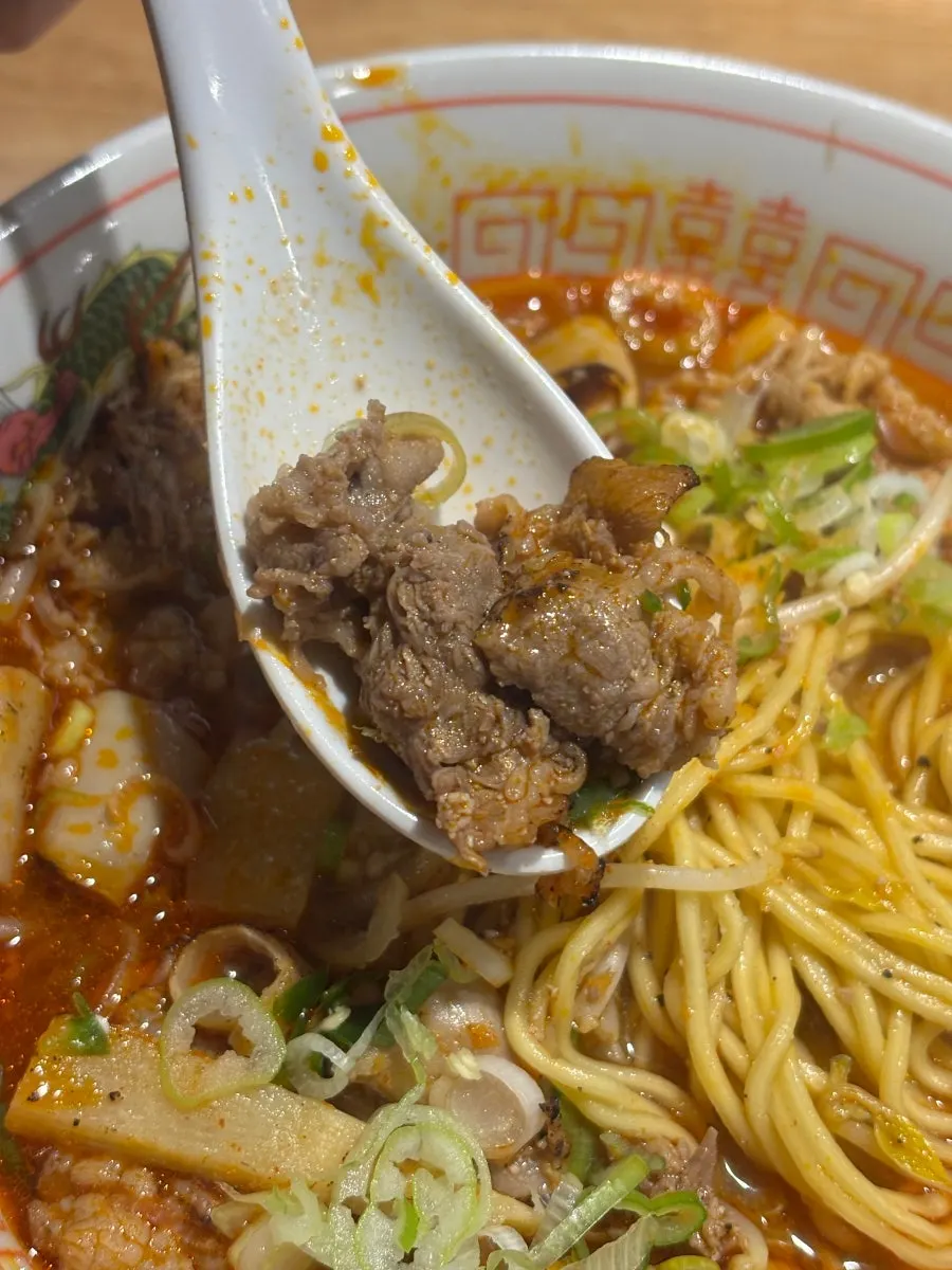 Lifting up a serving of thin noodles from the motsu ramen