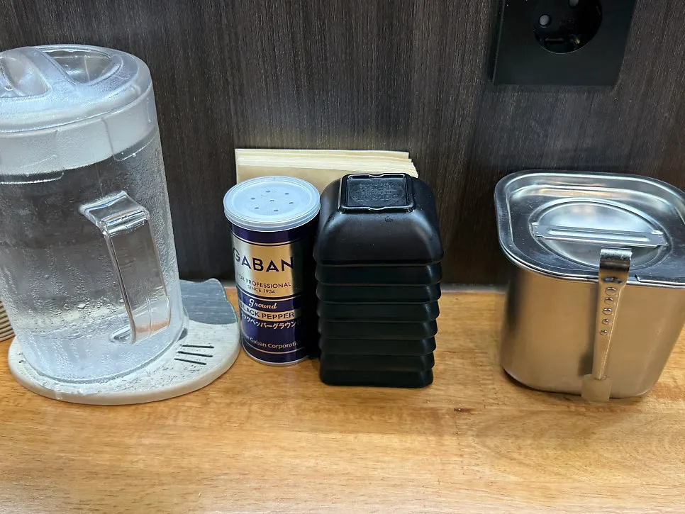 Water, side dishes and pepper set out at a bar seat