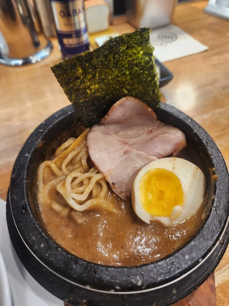 Thin straight noodles of the shoyu ramen lifted with chopsticks