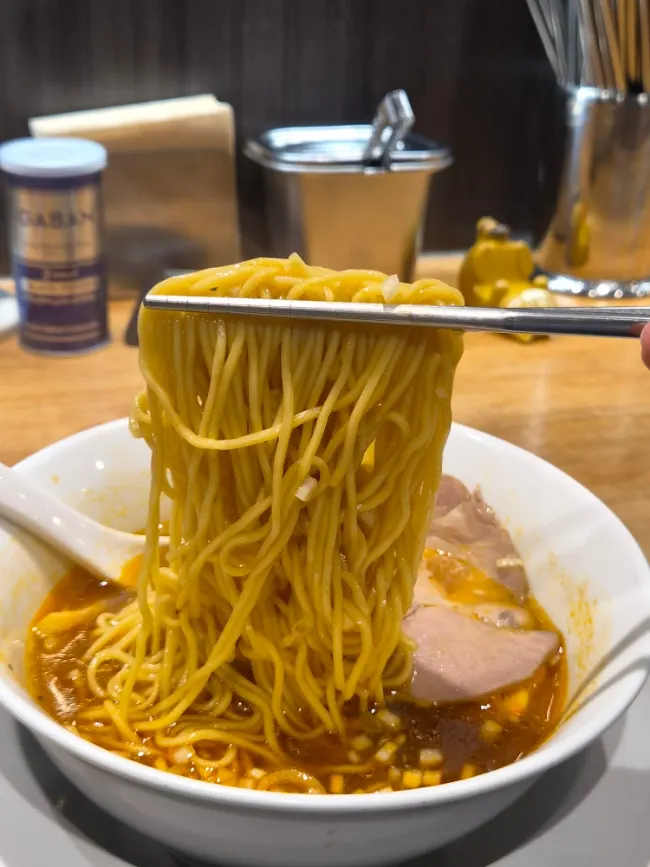 A spoonful of broth lifted from the spicy soy ramen