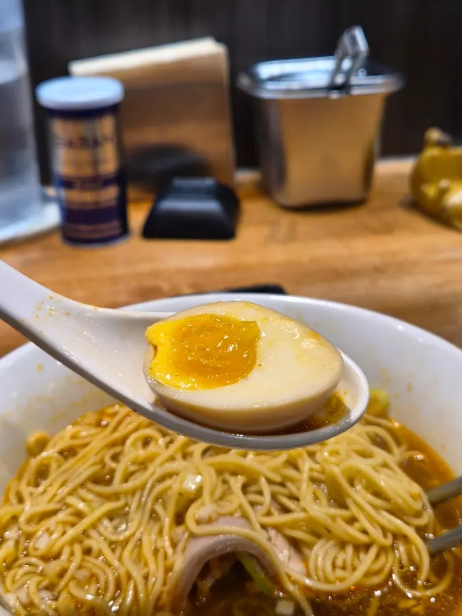 Noodles and chashu lifted together with chopsticks