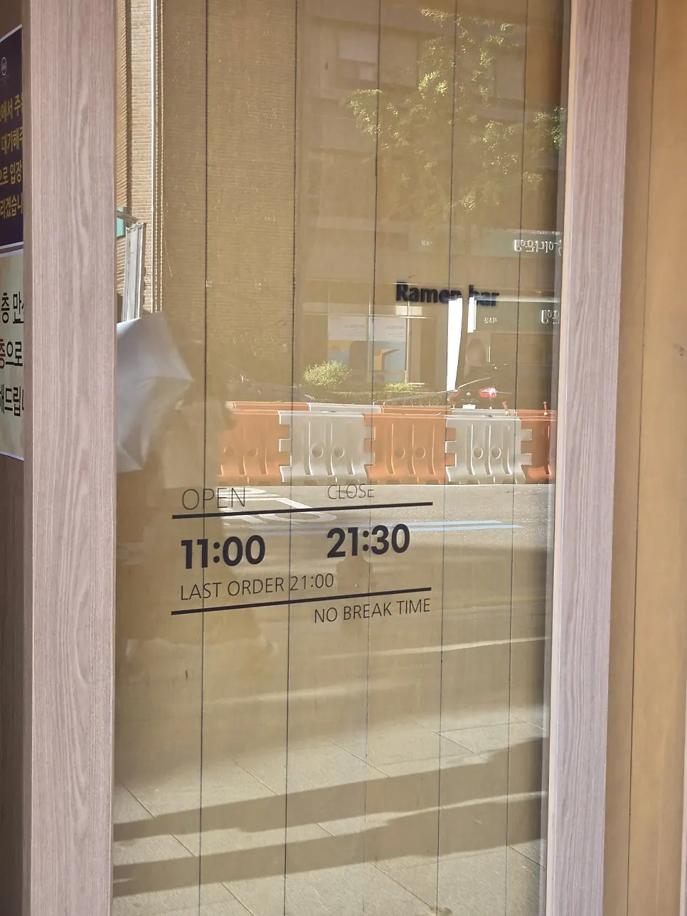 Storefront entrance with a sign showing hours and no break time