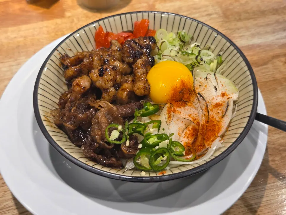 A bowl of hormone-don beef intestine rice bowl topped with egg yolk