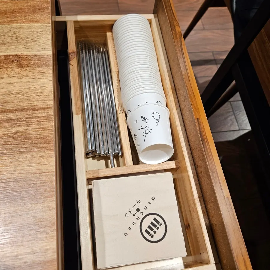 Drawer beside the table with chopsticks and paper cups