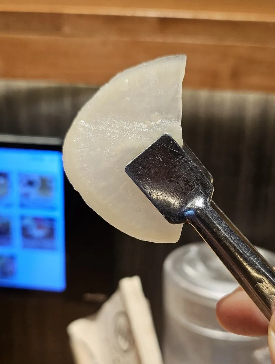 A bite of motsu ramen with intestine picked up on chopsticks