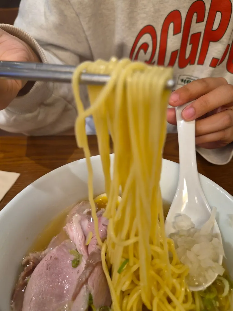 Vertical photo of shio ramen noodles being lifted