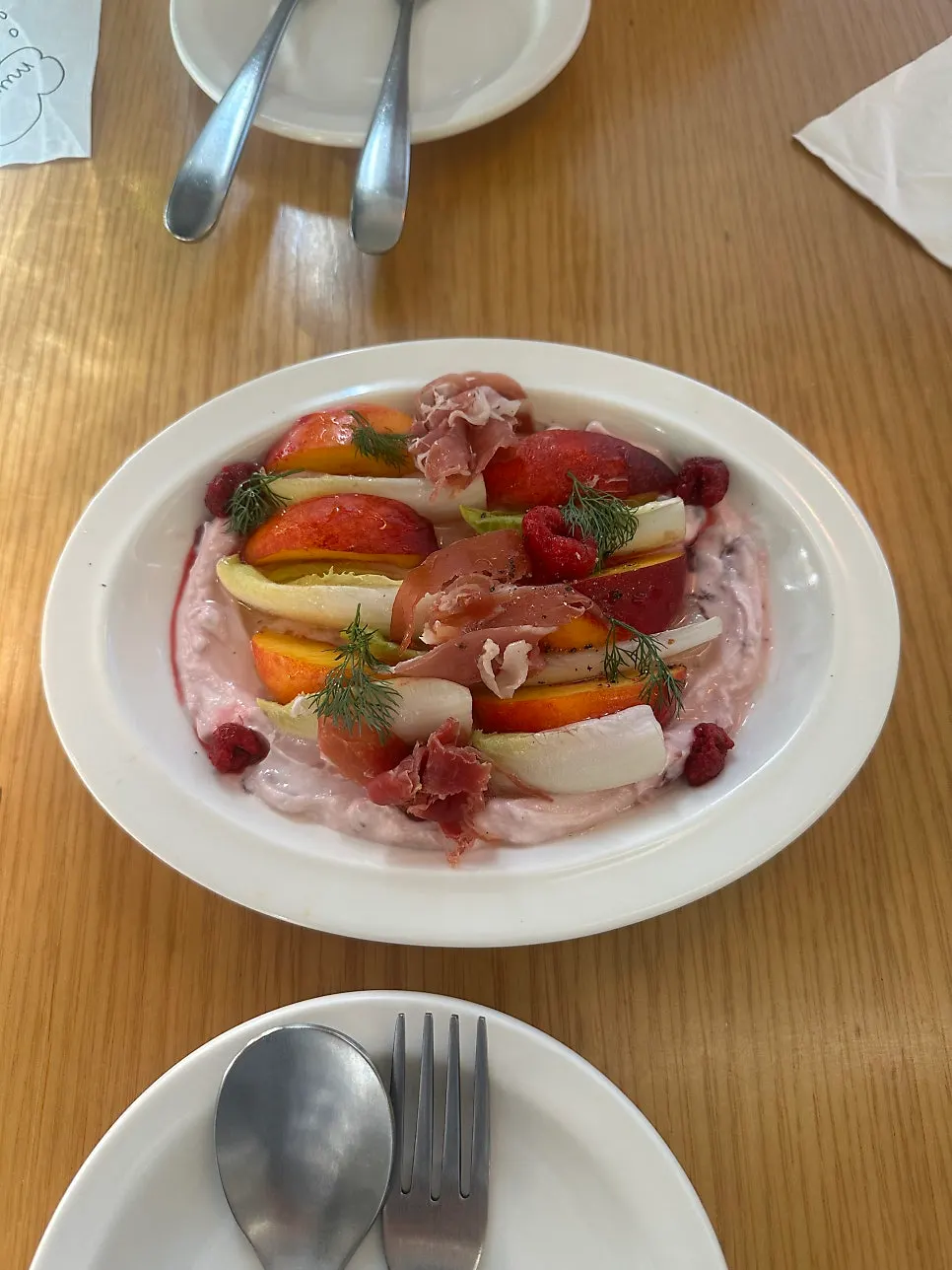 Close-up of salad topped with jamón and peach