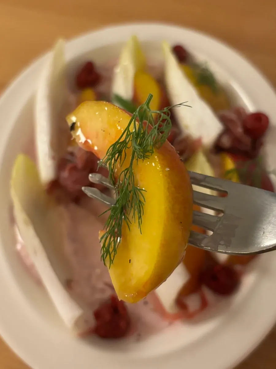 Endive salad topped with raspberries and plums
