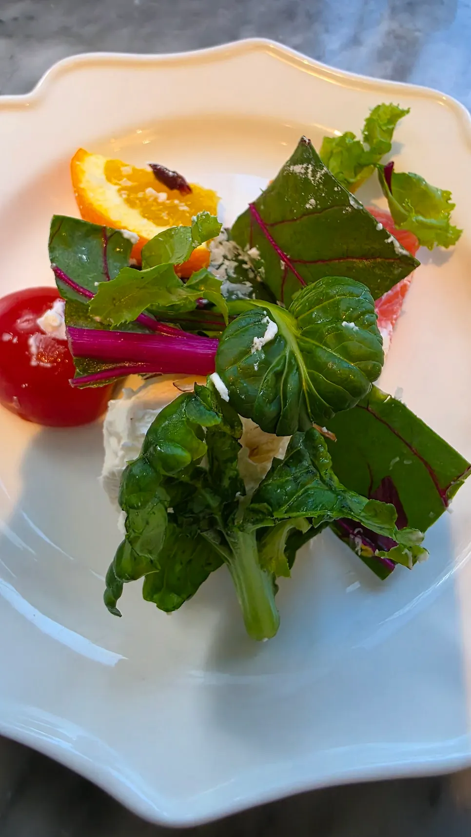 Salad topped with seasonal fruit and ricotta cheese