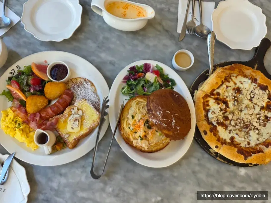 Meja dengan brunch, pasta, dan pizza tersaji