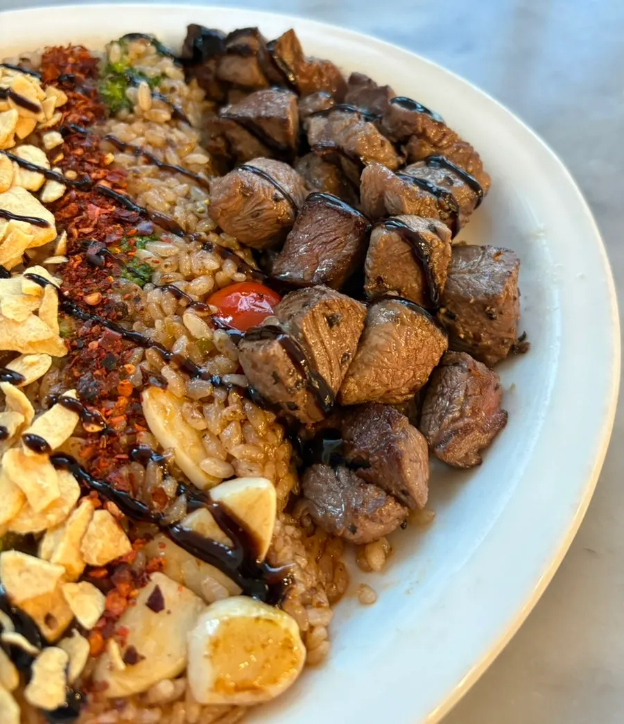 Close-up cube steak pilaf dengan taburan keripik bawang putih
