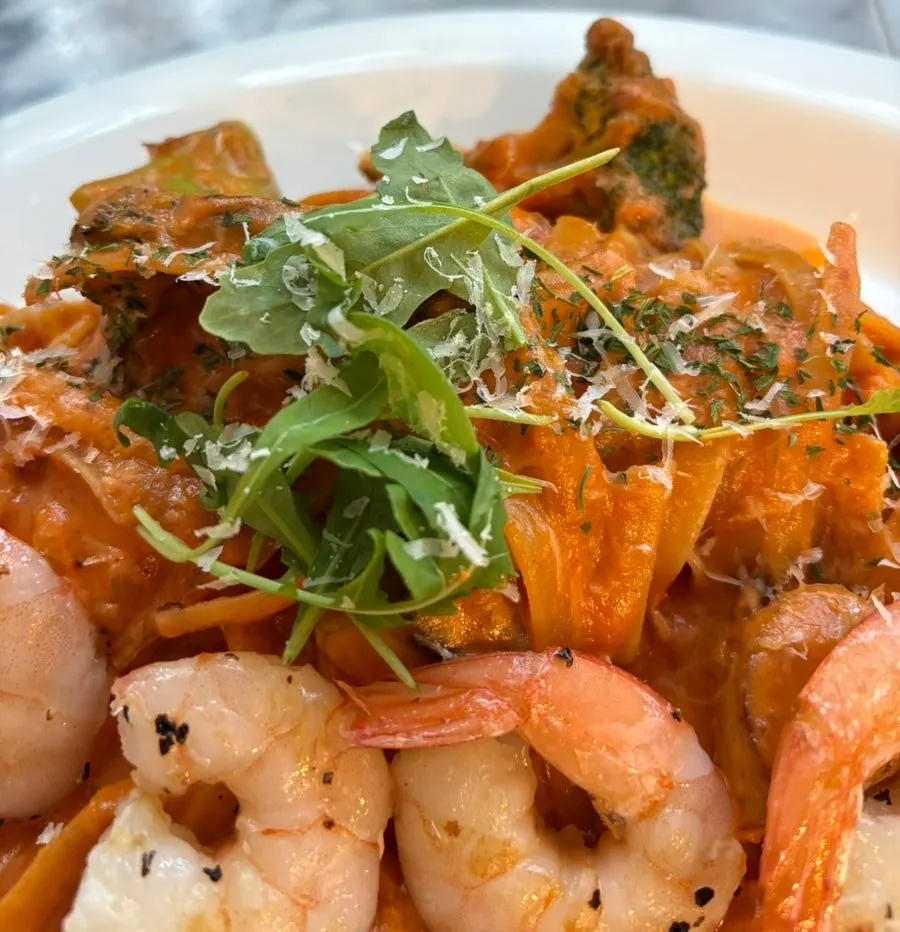 Close-up rosé pasta dengan tambahan keju dan herba