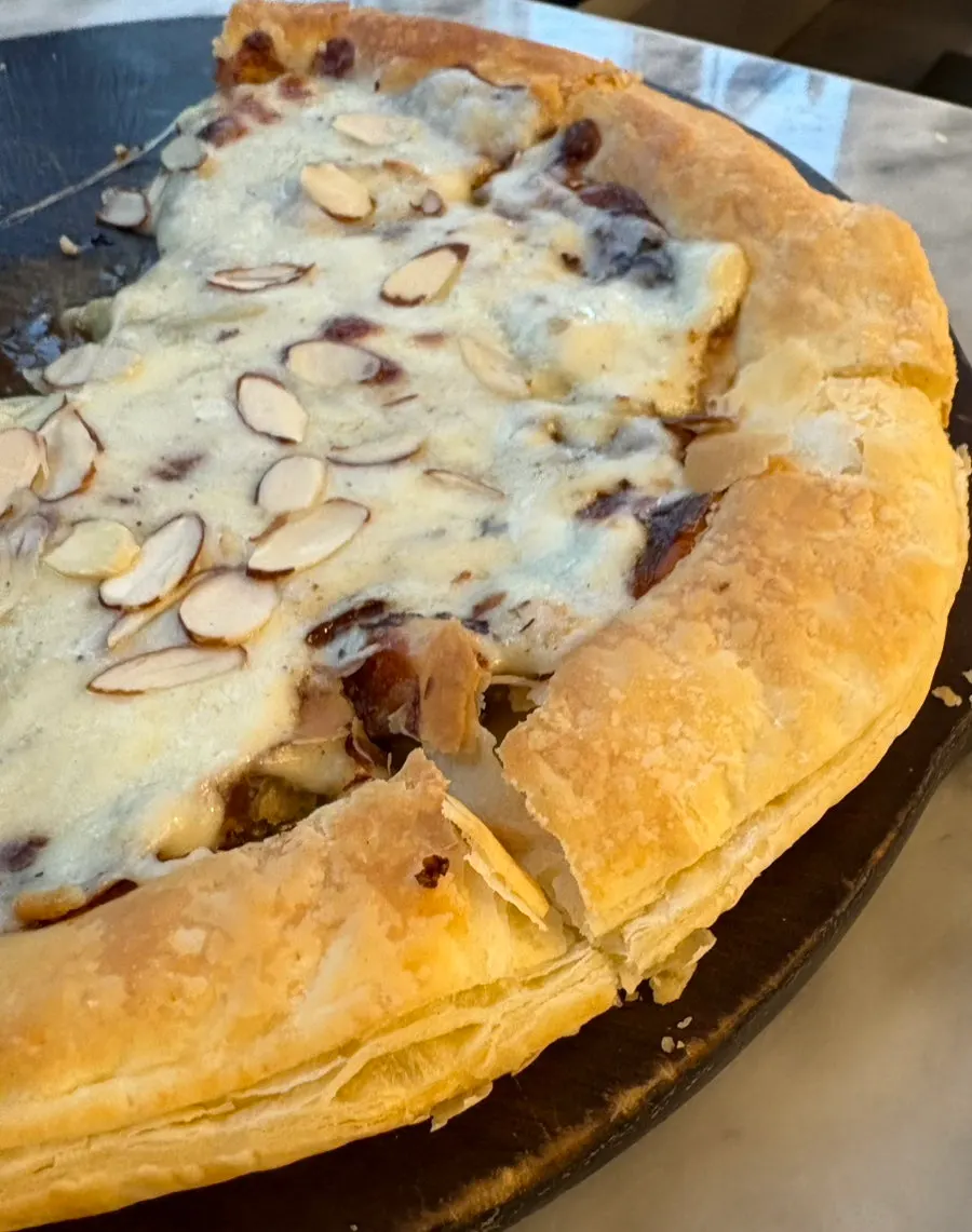 Close-up potongan pizza dengan almond dan keju