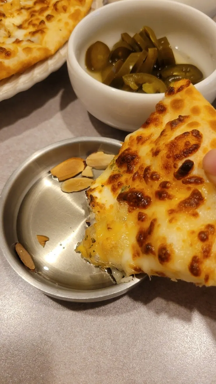 Close-up of quattro cheese pizza topped with almond slices