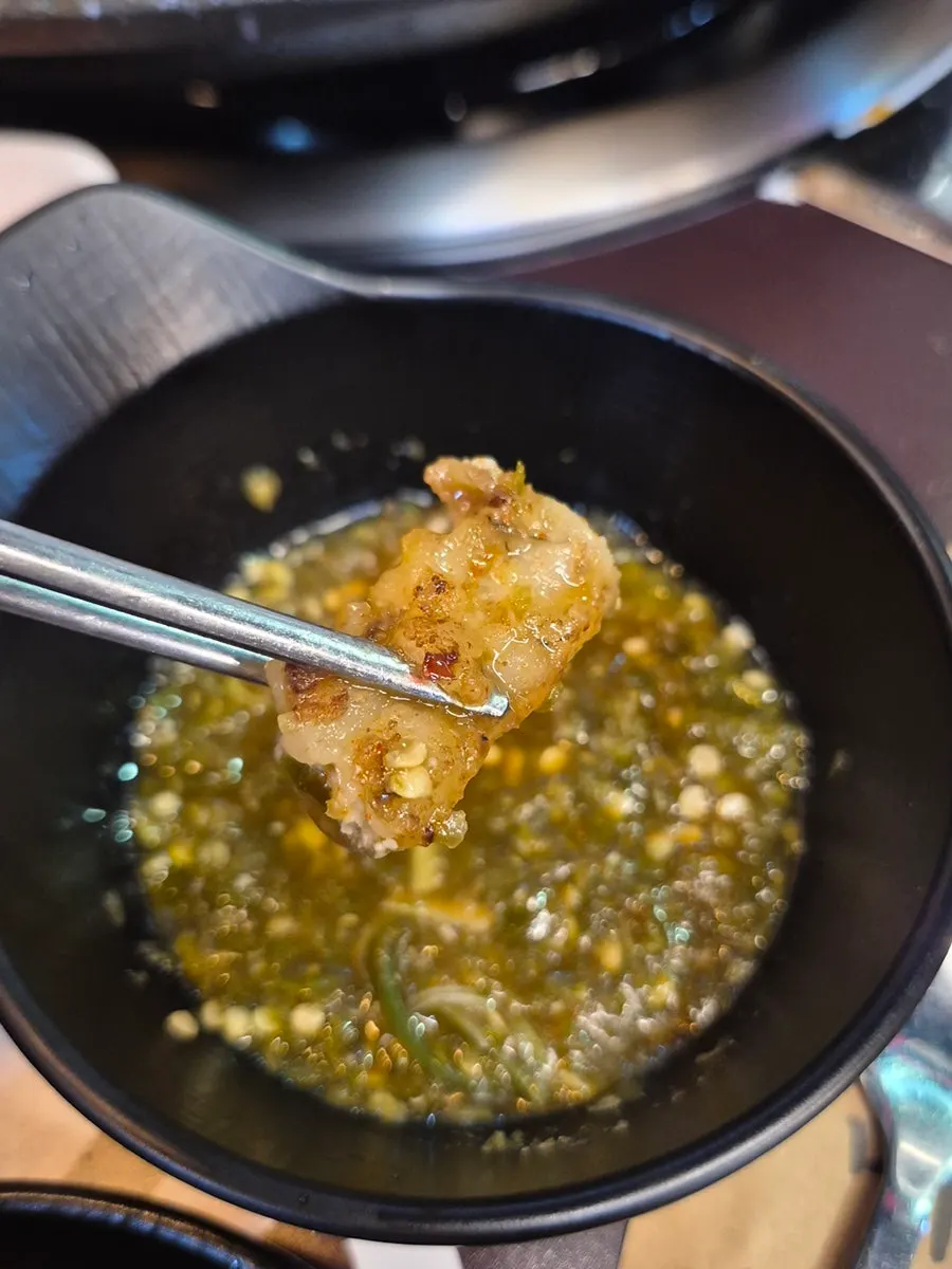 Grill with kimchi, chives, and potato cooking alongside the meat
