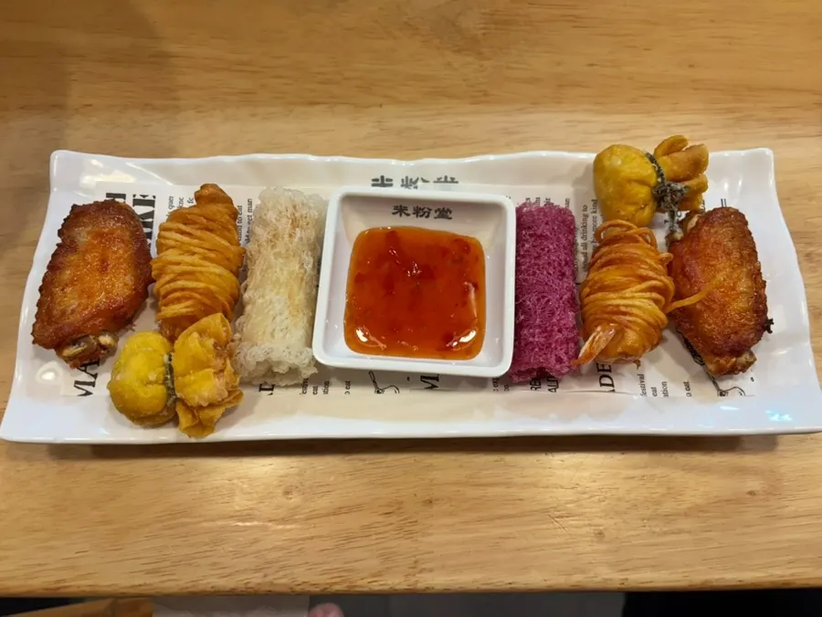 Mixed appetizer platter with buffalo wings, shrimp potato rolls, sweet potato spring rolls, and wedding siu mai