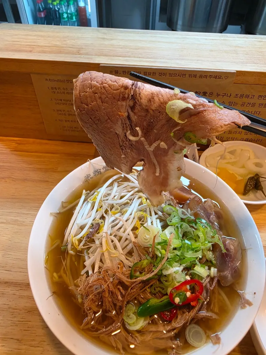 Noodles lifted up from a bowl of Mibundang pho