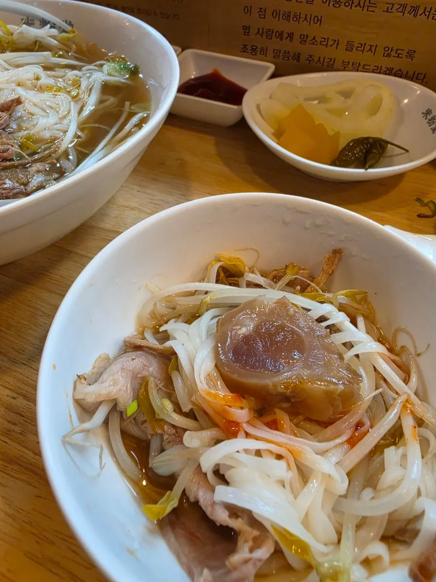 Mixing sauce into pho on a side plate