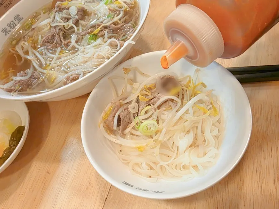 A small plate of pho with added hot sauce