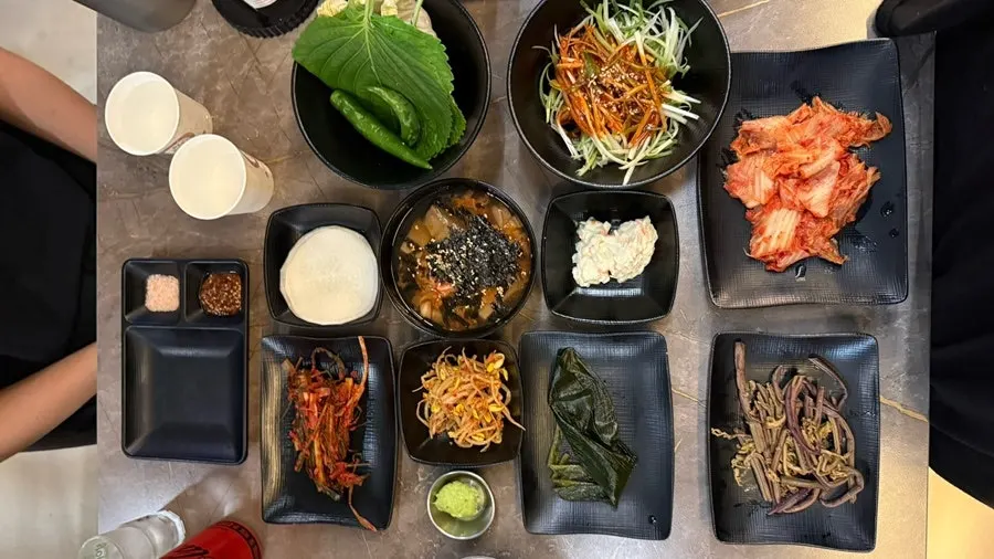 Table of basic side dishes including perilla leaves, seasoned green onion, wild garlic leaves