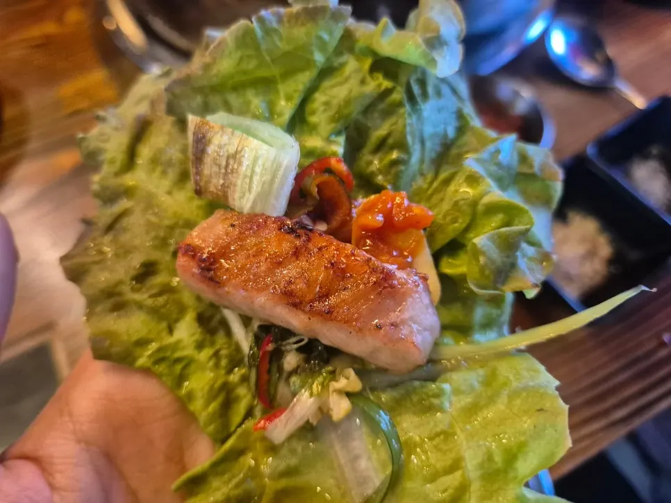 A bottle of soju alongside the meat