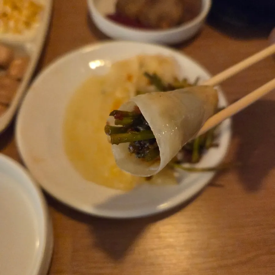A bite of flat dumpling wrapped with minari