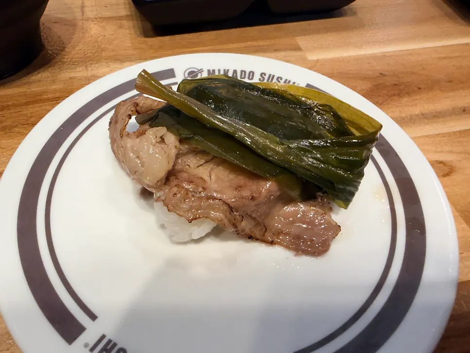 A plate of beef brisket with wild garlic sushi