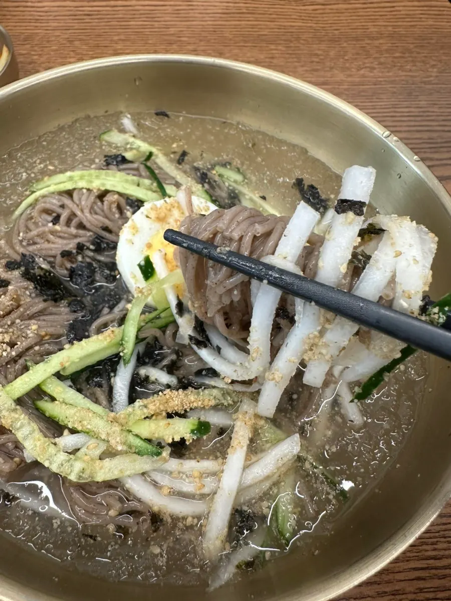 Mul makguksu topped with cucumber and egg garnish
