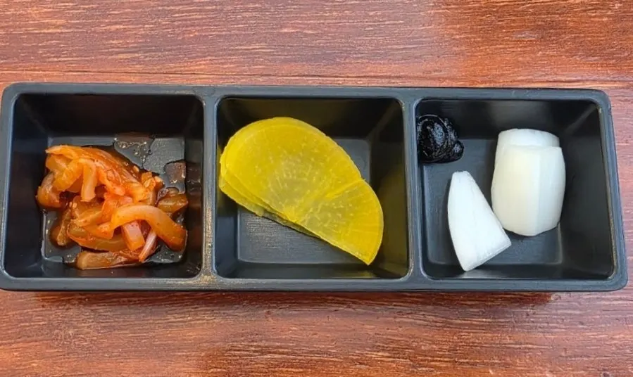 Basic side dishes: danmuji, jjachai, and onions set on the table