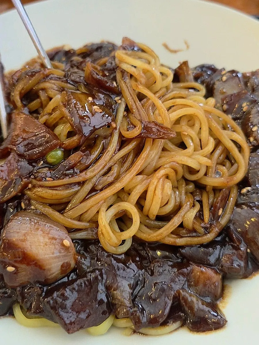 Close-up of jjajangmyeon noodles mixed with sauce