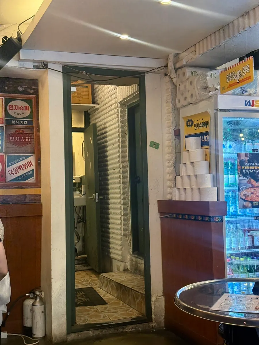 Old-style advertising posters covering a wall at Minji Superette